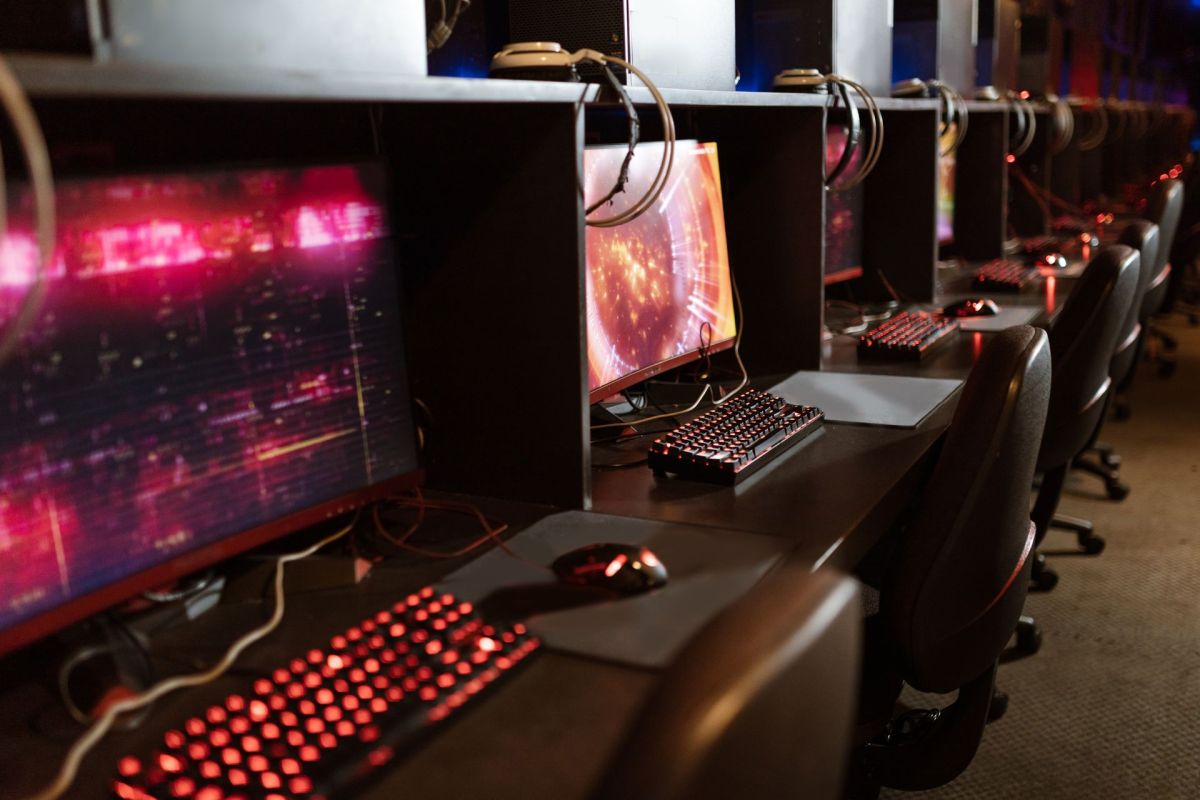 A row of gaming PCs with backlit keyboards and headsets