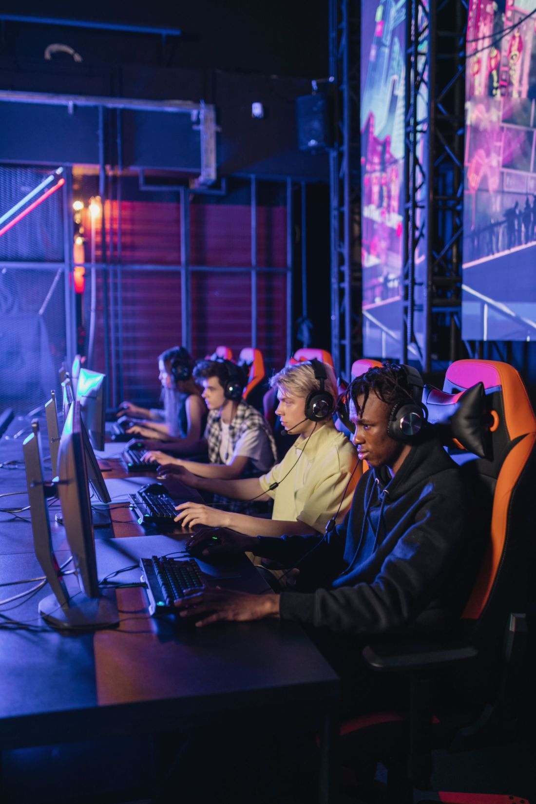 A row of players wearing headsets, competing at gaming PCs