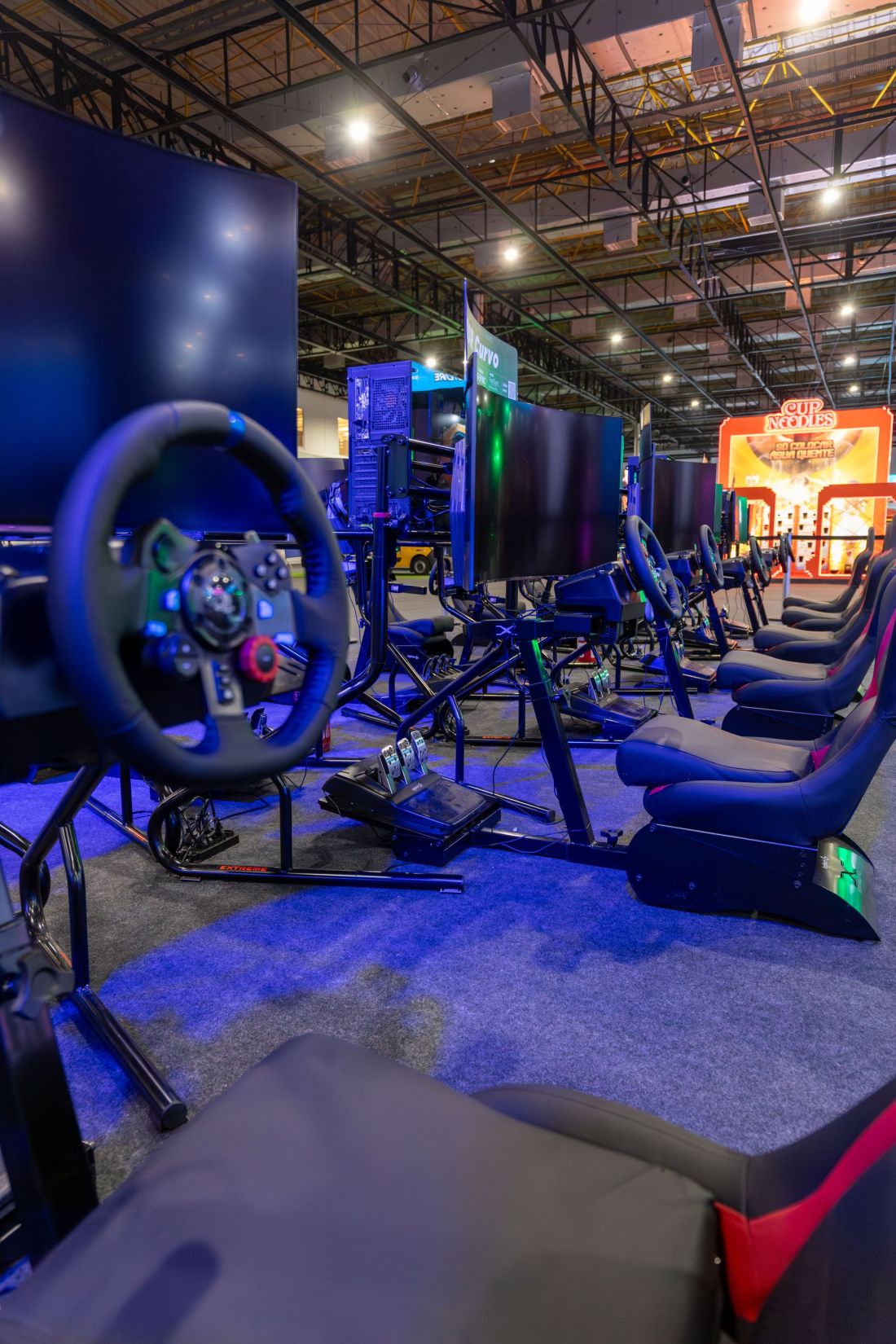 A row of racing-simulator rigs with steering wheels and pedals