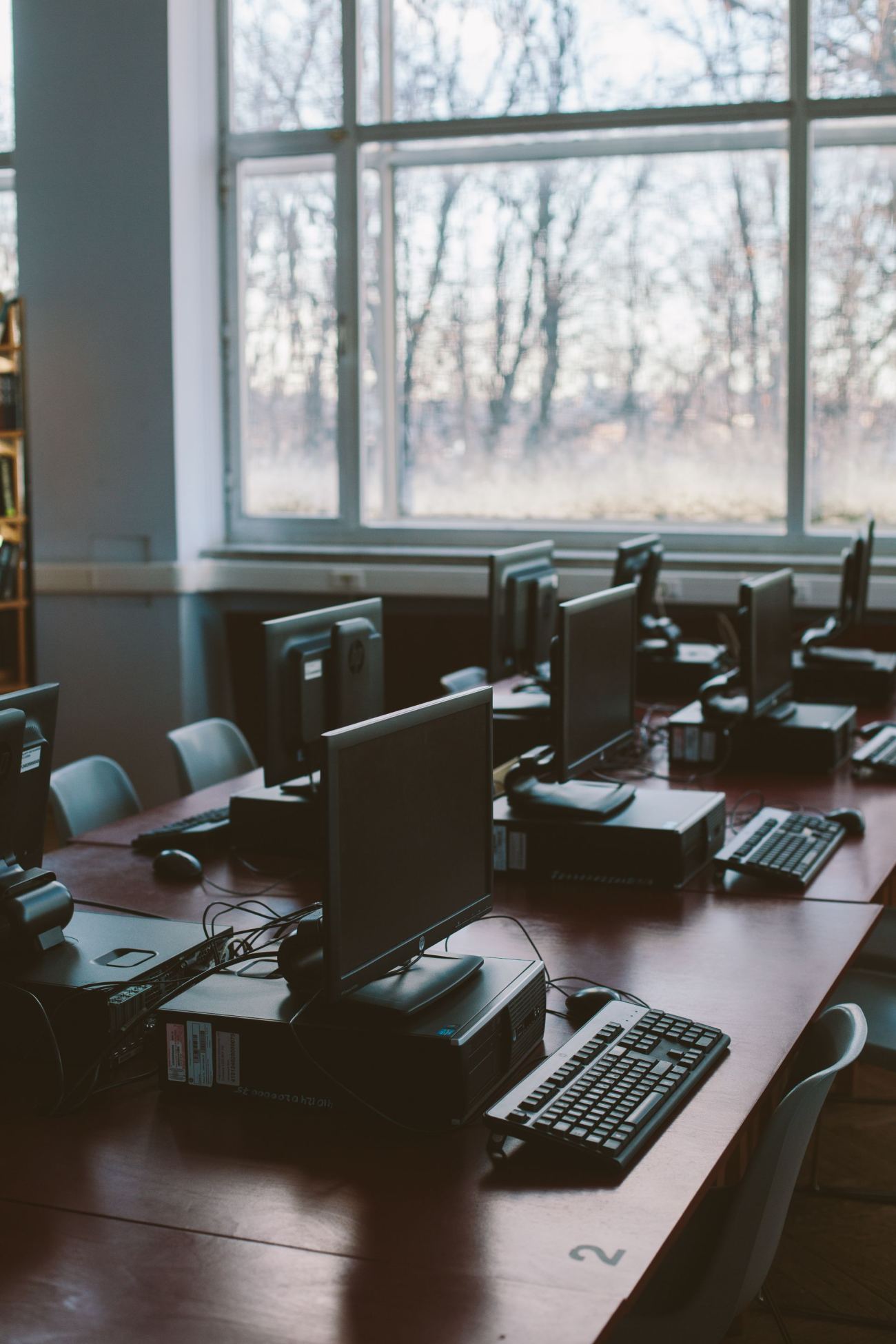 Public computer terminals beside library bookshelves