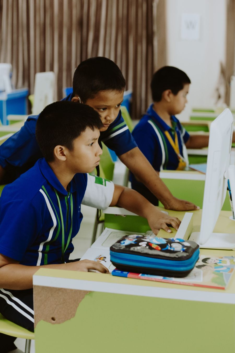 Two students at a computer, one pointing at the screen