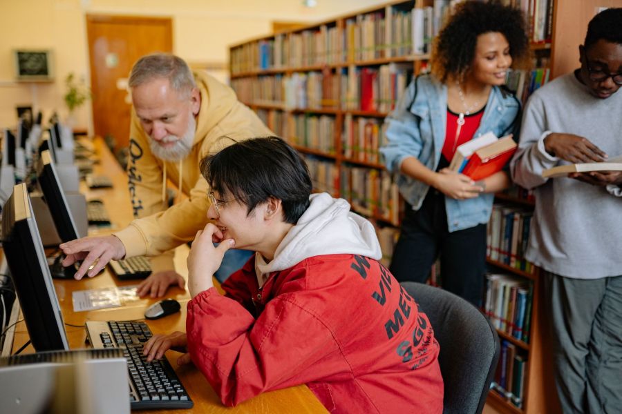 A staff member helping a student at a campus library computer terminal